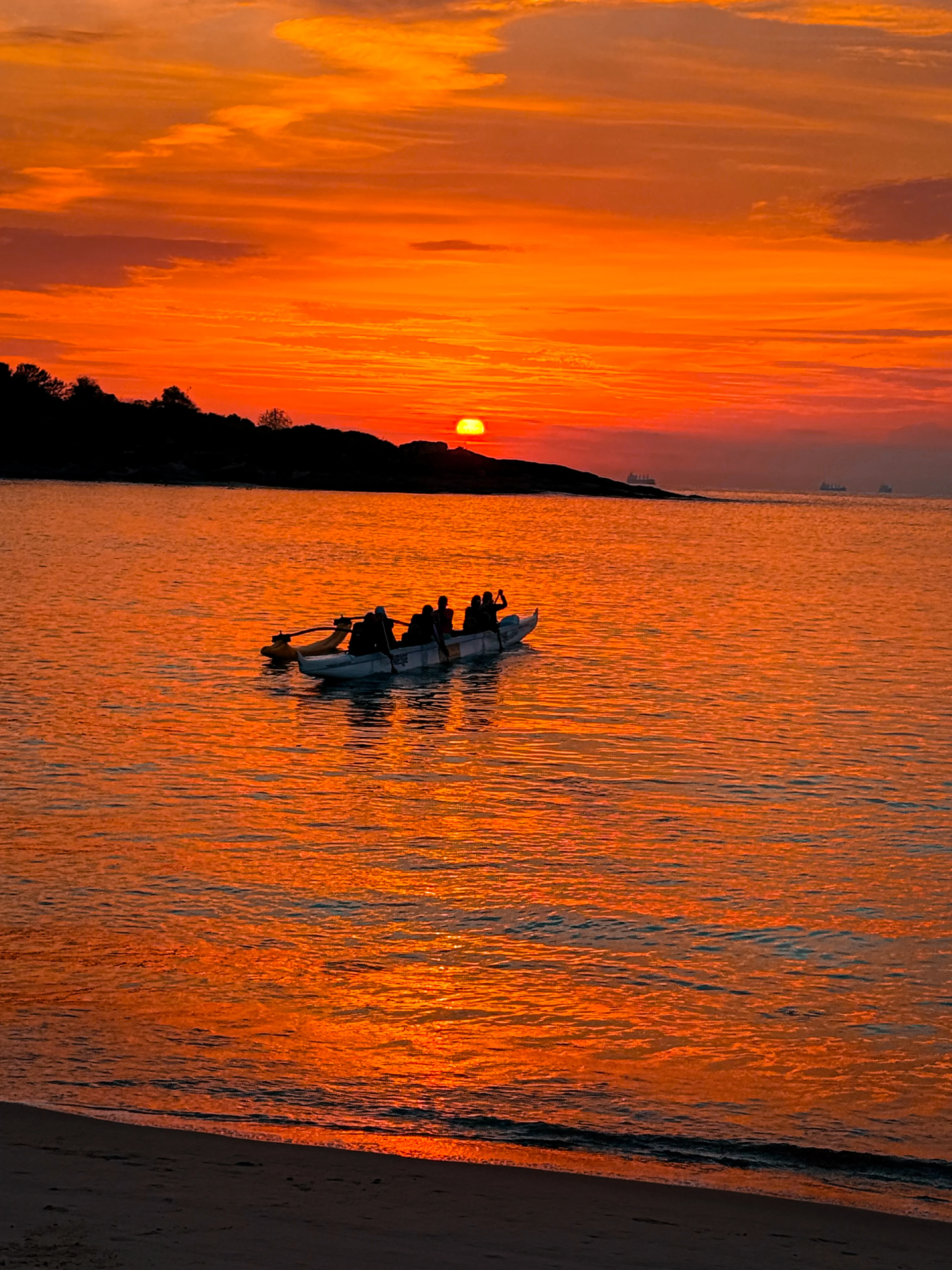 Silhueta da canoa havaiana no mar durante o pôr do sol alaranjado